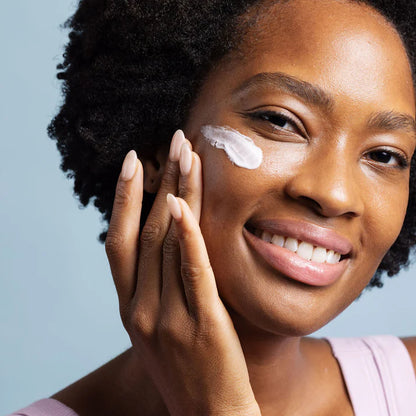 Woman applying cream to her face with a blue background